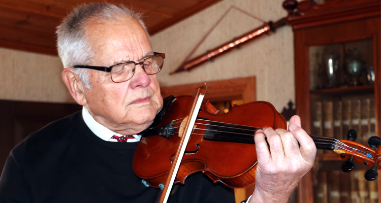Äldre man spelar koncentrerat på sin fiol