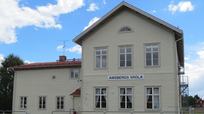 Amsbergsskola, vit byggnad med en skylt på fasaden där det står Amsbergsskola